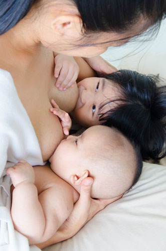 Tandem breastfeeding two baby children