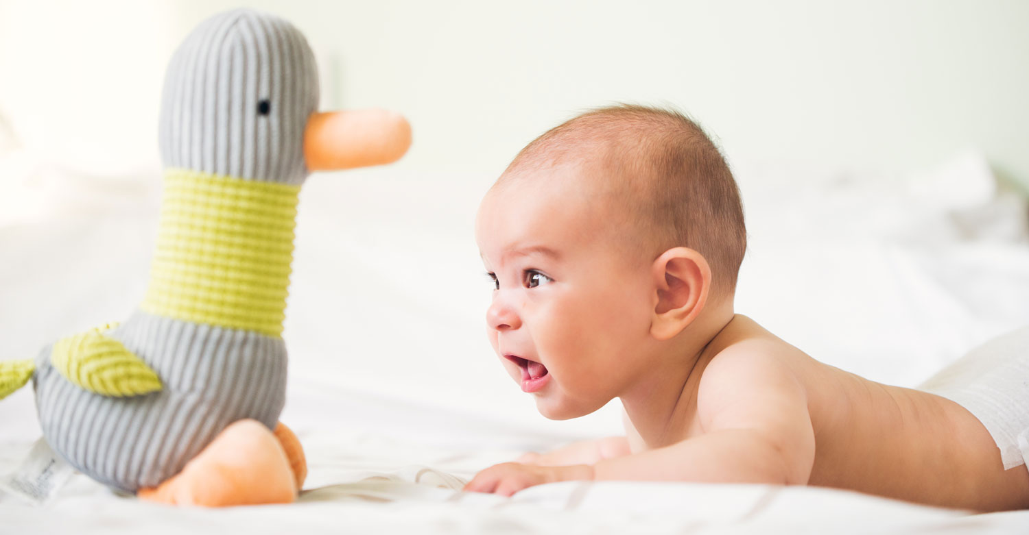 baby on tummy looking at toy